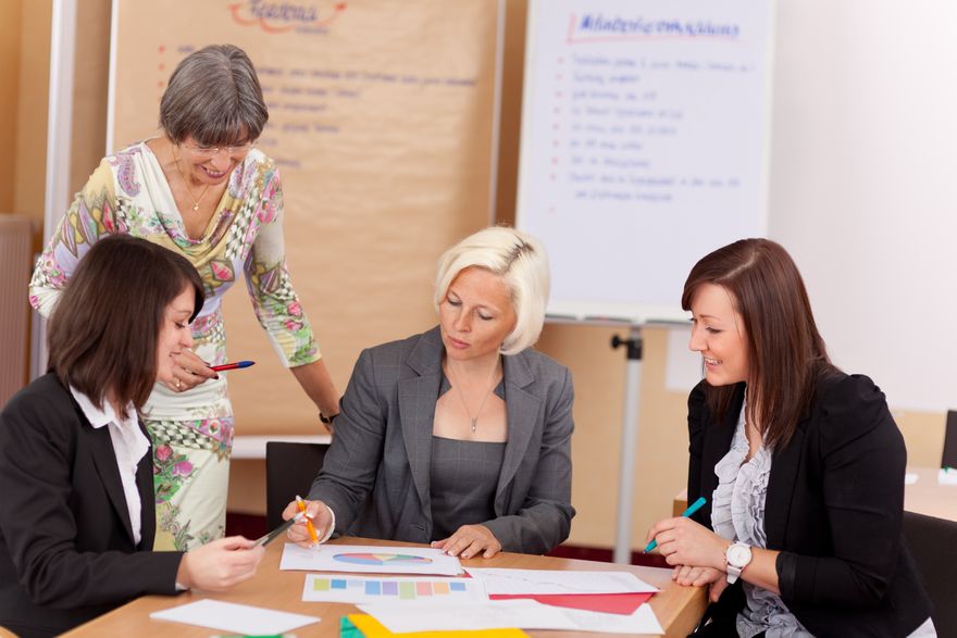 An ECU MED graduate sits at a table with other teachers. She is looking at files and running the meeting.