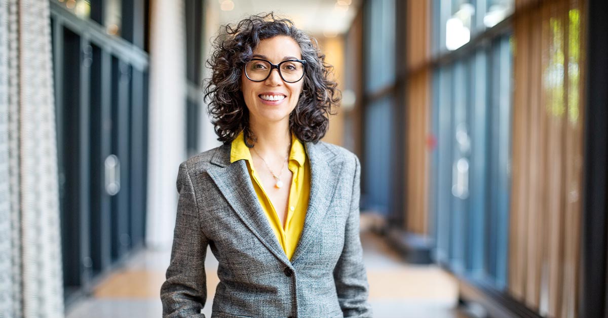 A professional woman in a business suit and glasses.