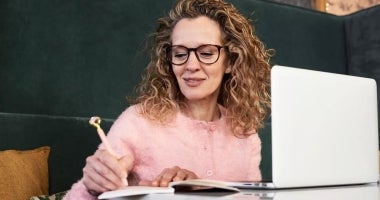 Middle-aged woman writing on a notebook.